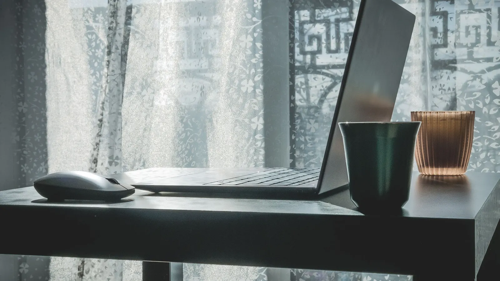 Modern laptop and wireless mouse on an office desk.